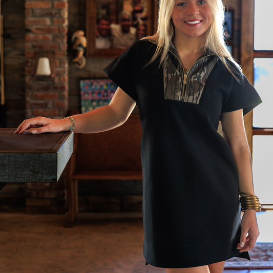 Woman wearing a black dress with Mossy Oak Bottomland camouflage accents in an indoor setting
