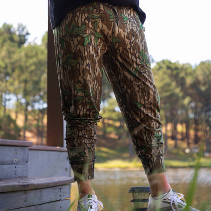 Men’s Mossy Oak camo joggers made with buttery soft performance fabric, athletic fit, and tapered leg design. 