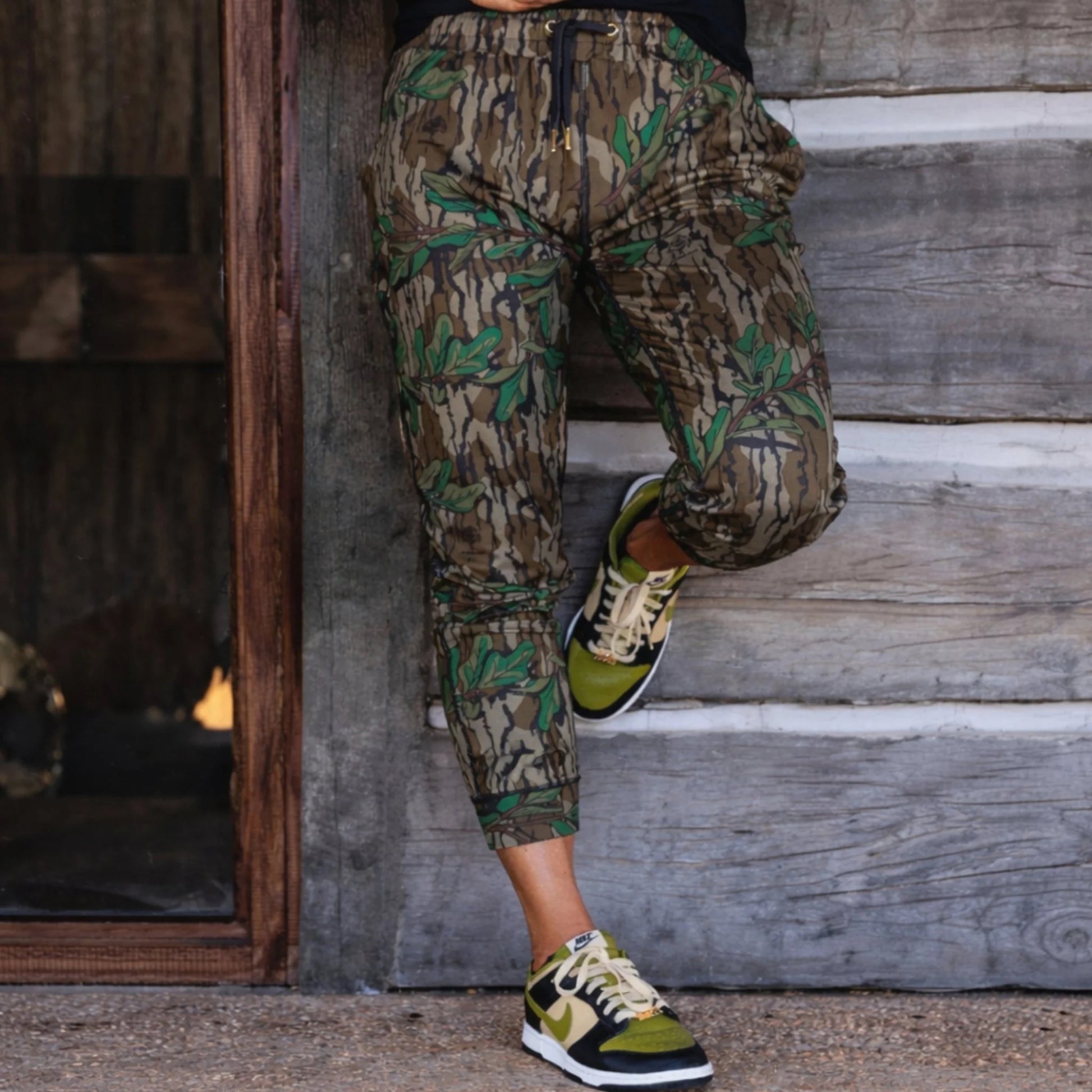 Women’s Mossy Oak camouflage joggers with gold drawstring end caps and grommet  accents, designed for elevated athleisure wear and outdoor performance.