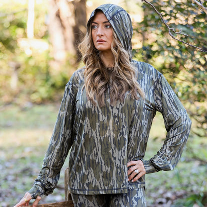 Full view of women’s camouflage hooded performance top styled outdoors 