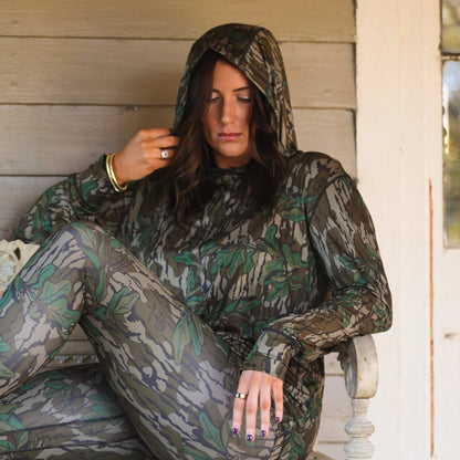 Model lounging in women’s camouflage hooded performance set