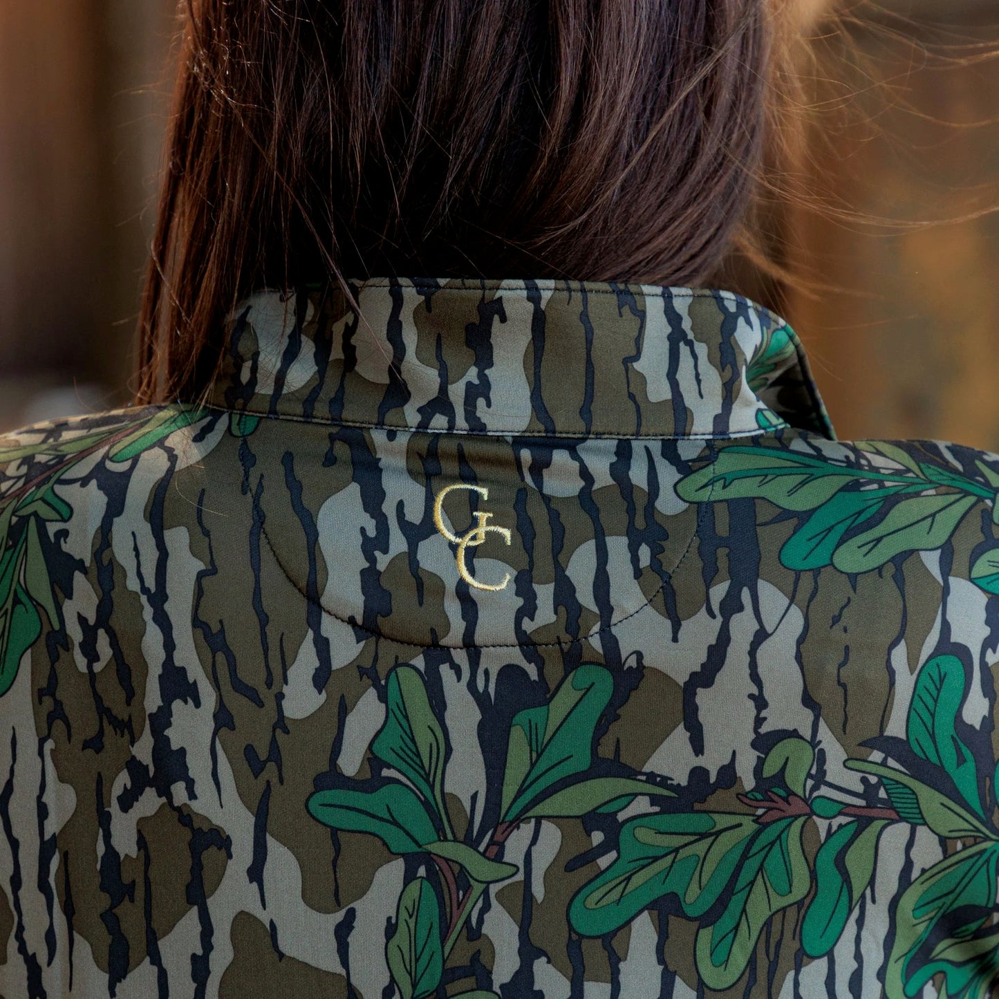 Back view of women’s camouflage half-zip top with embroidered logo, designed for outdoor performance and everyday athleisure. 