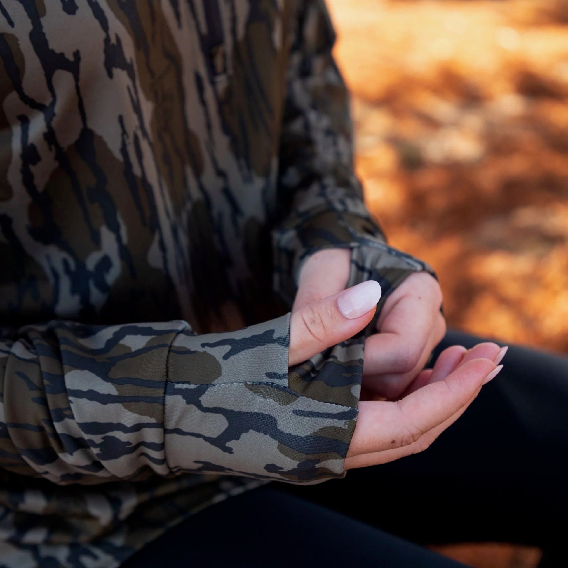 Close-up of women’s camo athleisure top showing thumb hole cuff and flexible performance fabric. 