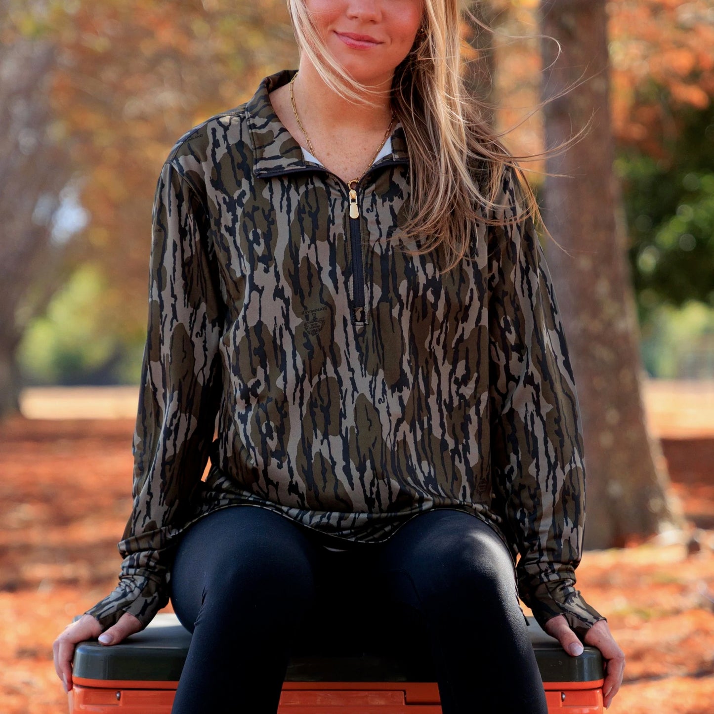 Women wearing camouflage long-sleeve performance pullover styled for outdoor lifestyle, featuring a relaxed athletic fit and lightweight fabric. 