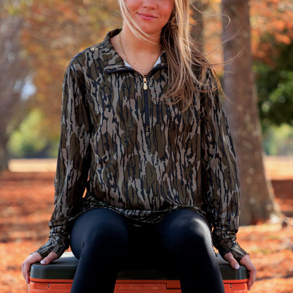 Women wearing camouflage long-sleeve performance pullover styled for outdoor lifestyle, featuring a relaxed athletic fit and lightweight fabric. 