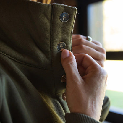 Close up detail of women’s quarter-snap pullover showcasing gold snap buttons to highlight Mossy Oak Bottomland camouflage pattern on the interior of the collar. 